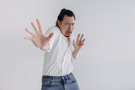 Fear face long hair Asian man bun in white shirt and jean stand on white.の写真素材