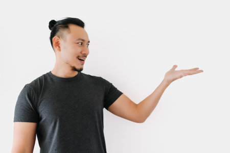 Happy Asian freelance man bun hair in black with thing in hand on white.の写真素材