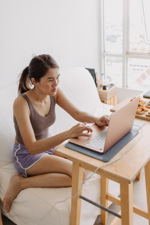 Asian woman is working at home with cozy clothes and breakfast meal.の写真素材