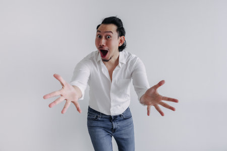 Surprised face long hair Asian man bun in white shirt and jean stand on whiteの写真素材