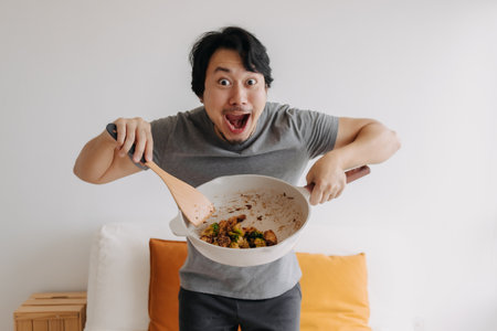 Happy asian man proud and present his homemade meal in the pan.の写真素材