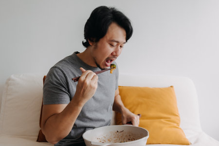 Asian man eating his homemade diet meal in the pan as it is his daily routine.の写真素材
