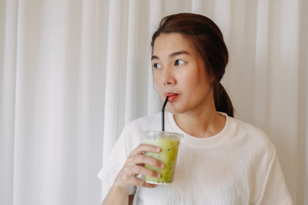 Happy healthy Asian woman drinking Iced Latte Matcha Green Tea.の写真素材