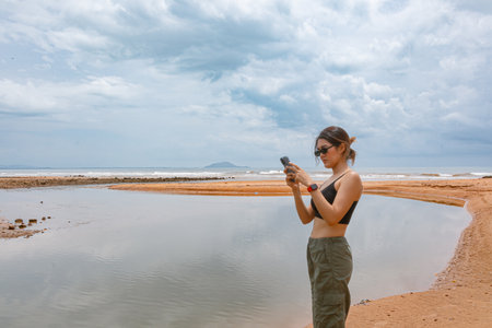 Asian woman taking photo with mobile phone on the beach.の写真素材