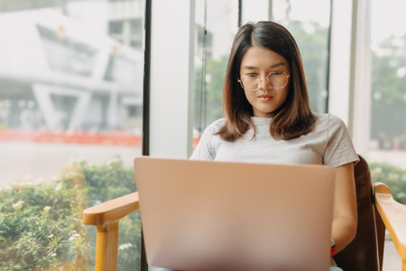Asian woman focus on working her job online, in the public coffee cafe.の写真素材