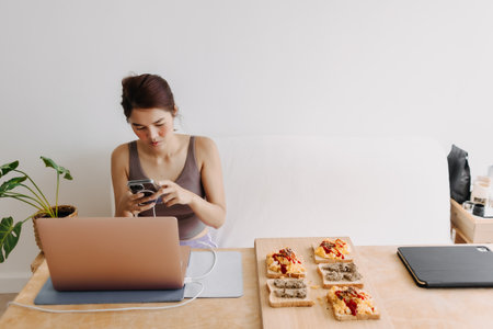 Asian woman working at home got distracted with the mobile phone.の写真素材