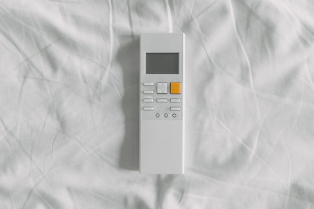 White Air condition remote control on white bed sheet.