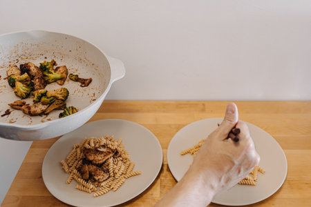 Asian man preparing two dishes of homemade pasta in his small kitchen.の写真素材