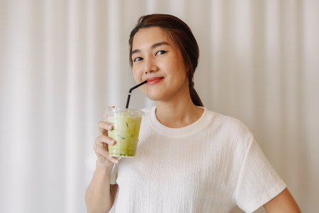 Happy healthy Asian woman drinking Iced Latte Matcha Green Tea.の写真素材
