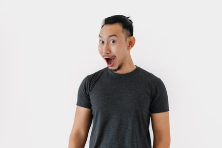 Surprised wow face Asian freelance man bun hair in black on white.の写真素材