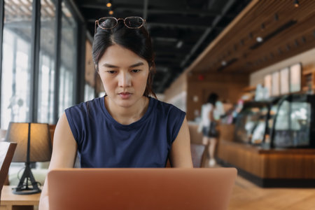 Portrait of Asian woman working remotely on computer laptop in co-working space.の写真素材