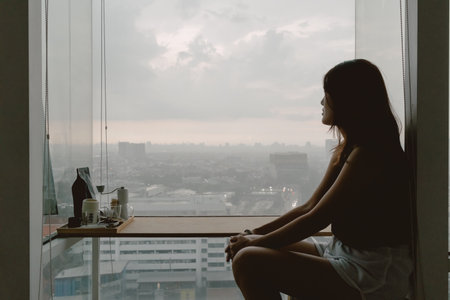 Introvert single asian woman sitting looking out the view enjoy being alone.の写真素材