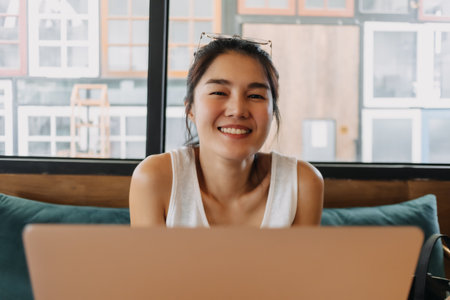 Happy Asian woman enjoy working online remotely from a co-working space cafe.の写真素材