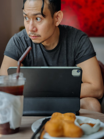Portrait of freelance Asian man working online with iced coffee in the cafe.