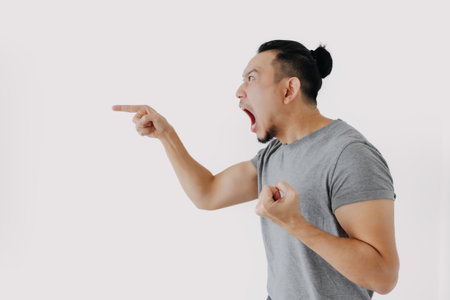 Angry and furious shouting face of Asian man in grey t-shirt isolate on white.の写真素材
