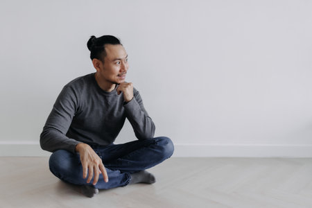 Happy creative freelance Asian man sitting on the floor smile and looking out.の写真素材