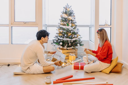 Asian husband and wife couple lover decorating Christmas tree together while the man helping woman packing decoration boxes.の写真素材
