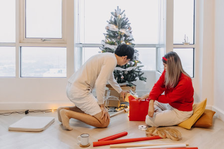 Asian husband and wife couple lover decorating Christmas tree together while man setting up the tree and woman packing the box.の写真素材
