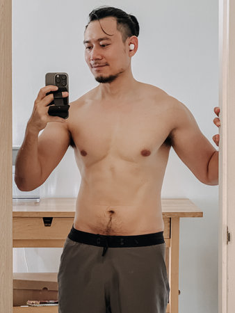 Healthy man taking selfie photo with bathroom mirror showing of his body.の写真素材
