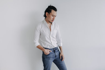 Sad face long hair Asian man bun in white shirt and jean stand on white.の写真素材