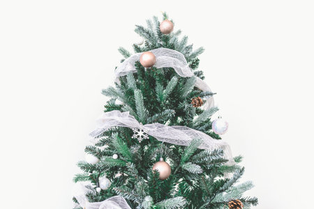Decorated Christmas pine tree decorated with white gold ornaments and garlands isolated on white wall cerebrate for happy holiday and new yearの写真素材
