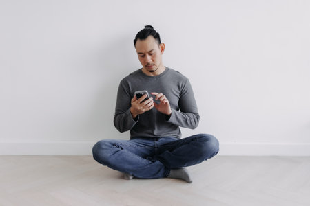 Creative freelance Asian man sitting on the floor looking at the phone.の写真素材