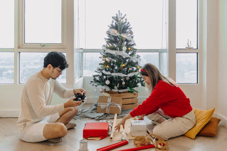 Asian husband and wife couple lover decorating Christmas tree together while man checking light balls and woman packing box.の写真素材
