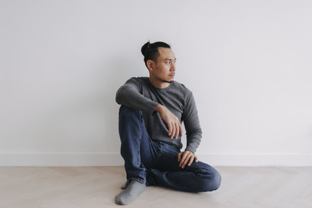 Lonely Freelance creative Asian man sitting alone in empty white room.の写真素材