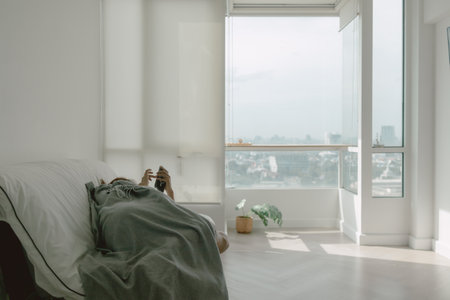 Asian woman taking a nap using phone in her apartment on weekends.の写真素材