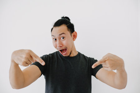 Wow and impressive Asian man hand pointing in black t-shirt isolate on white.の写真素材