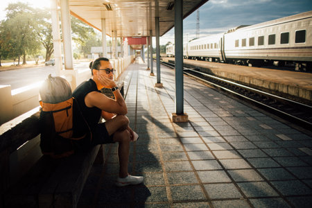 Asian man tourist backpacker sit at the platform wait for the train.の写真素材