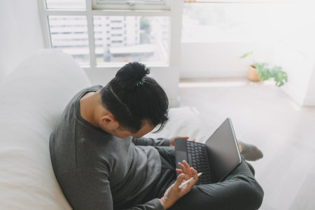 Freelance digital nomad Asian man work online at home but feel sleepy.の写真素材