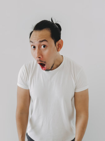 Vertical photo of funny shock and surprise face Asian man in white t-shirt.