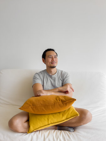 Portrait of happy Asian man relax on the sofa in his living room.