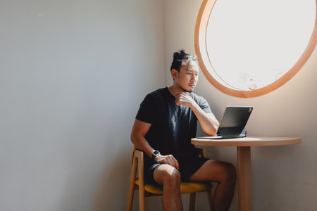 Freelance Asian man work online on computer tablet at corner of cafe.の写真素材