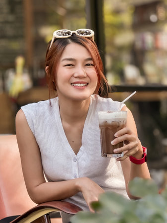 Happy smile Asian woman drink iced cocoa while working online in the cafe.の写真素材