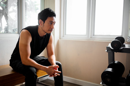 Tired athlete seated by window cooling down after training