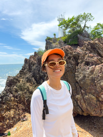 Tourist posing happily near rocks with ocean and sky in the backgroundの写真素材