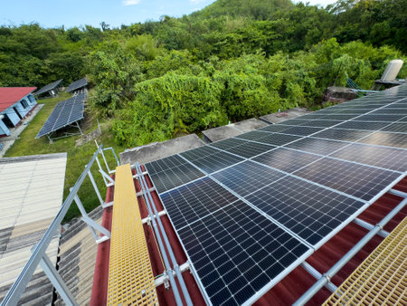 Red-roofed building with solar panels installed under clear sky in natural settingの写真素材