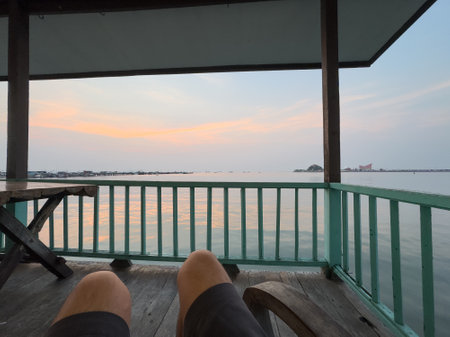 POV, point of view of a man sitting on rocking chair and looking at the sunset sea view in Thailand.の写真素材