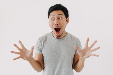 Young Asian male expresses surprise with dramatic body language indoorsの写真素材