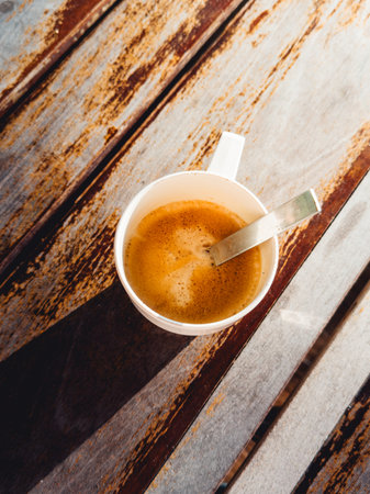 Steaming espresso cup placed on rustic wooden table in natural lightの写真素材