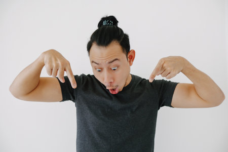 Wow and impressive Asian man hand pointing in black t-shirt isolate on white.