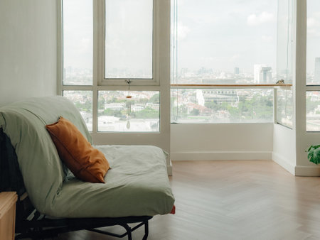 Green folding sofa bed with brown pillow in cozy living apartment.の写真素材