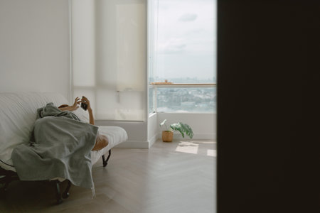 Asian woman taking a nap using phone in her apartment on weekends.の写真素材