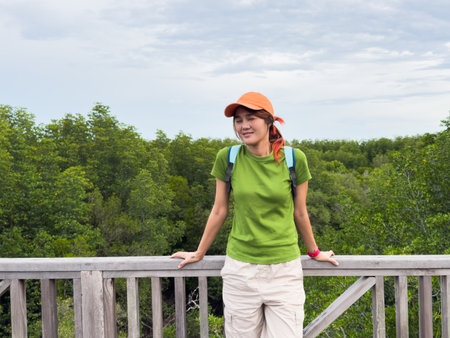 Side view of female traveler admiring nature on a wooden path surrounded by greeneryの写真素材