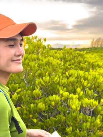 Woman in orange cap enjoying nature while glancing to the side with a soft smileの写真素材