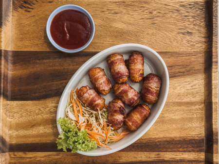 Set of sausages wrapped in bacon served on wooden plate.の写真素材
