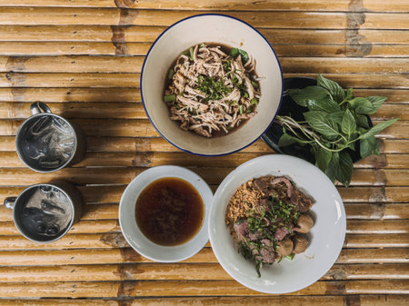 Various Asian noodle soups and side dishes served on bamboo table surfaceの写真素材
