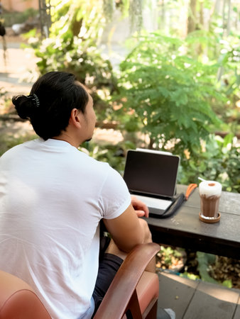 Happy freelance Asian man working online on his tablet computer in the cafe.の写真素材